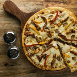 Delicious chicken and mushroom pizza on wooden board, perfect for food enthusiasts.