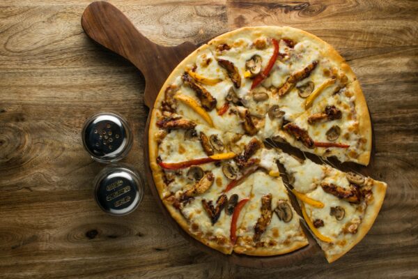 Delicious chicken and mushroom pizza on wooden board, perfect for food enthusiasts.