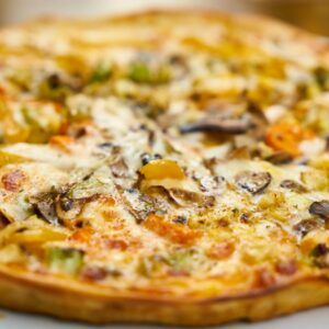 Mouth-watering close-up of a freshly baked veggie pizza with mushrooms and bell peppers.