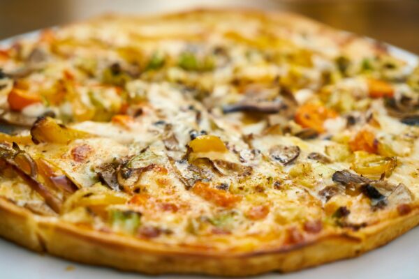 Mouth-watering close-up of a freshly baked veggie pizza with mushrooms and bell peppers.