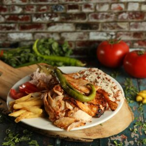 A mouthwatering plate of Turkish doner kebab with fries, rice, and vegetables in a rustic setting.
