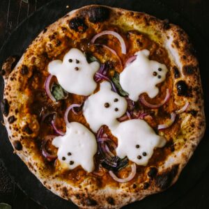 A spooky pizza decorated with ghost-shaped mozzarella, perfect for Halloween celebrations.