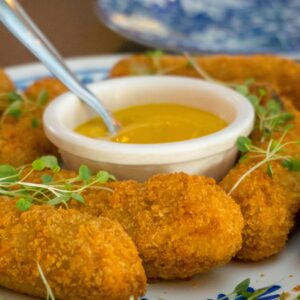 Delicious crispy potato croquettes served with a savory mustard dipping sauce, perfect for sharing.