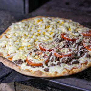 Freshly baked Brazilian pizza with diverse toppings including cheese, corn, and beef, cooked to perfection.