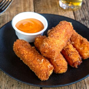 Delicious homemade mozzarella sticks with spicy dipping sauce, perfect for snack time.