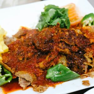 Delicious Iskender Kebab served with green peppers, fries, and tomato sauce.