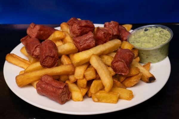 Tasty snack plate with crispy fries and sausages, perfect with creamy avocado dip.