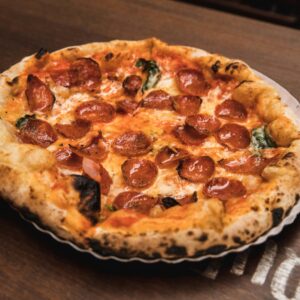 Close-up of a freshly baked pepperoni pizza with crispy crust on a wooden table.