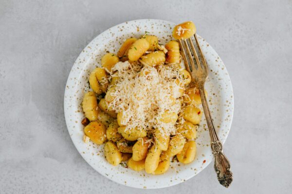 Delicious Italian gnocchi topped with grated Parmesan cheese, served on a ceramic plate.