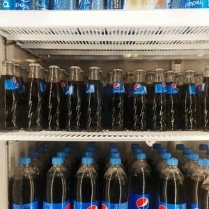 Stacked Pepsi bottles and cans arranged vertically in a refrigerator, showcasing a refreshing display.