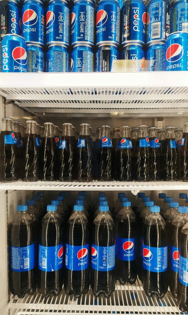 Stacked Pepsi bottles and cans arranged vertically in a refrigerator, showcasing a refreshing display.